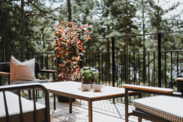 Sommar och sol på balkongen till Klockaruddssviten. Moderna skandinaviska terassmöbler med två kaffekoppar.