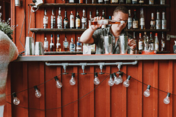 I baren står en bartender och häller upp en drink. Sjöbodens bar.