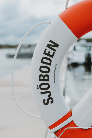 En boj i rött och vitt. skärgård och sommar. Sjöboden skärgårdskrog. Middag i skärgårdsmiljö intill havet. Mat och dryck i skärgårdsmiljö.